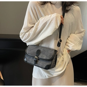 Vue latérale d'un sac bandoulière en tissu gris texturé avec finitions en cuir noir
