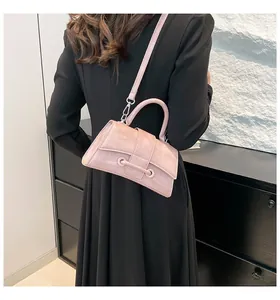 Detail of pink hourglass bag with glossy leather texture and curved bottom design