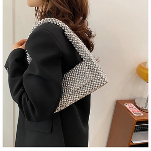 Close-up of sparkling silver rhinestone shoulder bag on a black blazer with hollow flip design