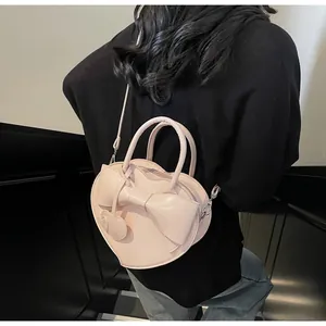 Detail of pink heart-shaped bag featuring a large bow and dual heart charms on the side