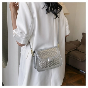 Detail of silver woven crossbody bag with metallic finish and gold hardware on white suit