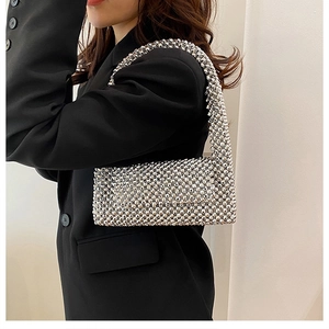 Detailed view of silver beaded handbag with metallic texture worn over the arm