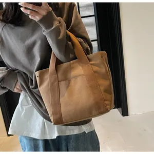 Detail of caramel canvas tote bag with reinforced metal rivets and exterior pocket