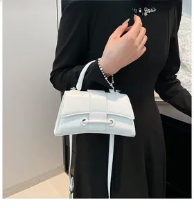 Close-up of minimalist white hourglass handbag with textured leather and crossbody strap