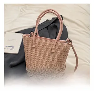 Detail view of pink woven tote bag with adjustable strap on white and grey background