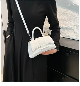 Close-up of a white glossy hourglass handbag with textured finish and metal ring buckle