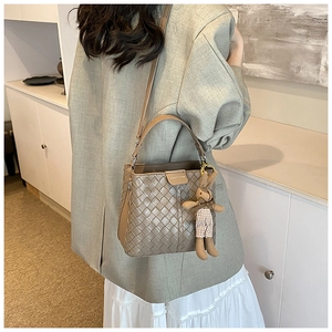 Close-up of woven bucket bag with adjustable strap and cute plush bunny charm