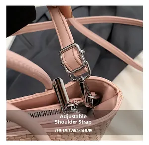 Detail of adjustable leather shoulder strap and silver metal buckle on woven pink bag