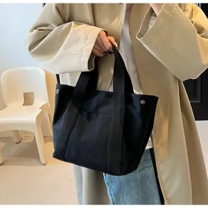 Detail of black canvas tote bag showing heavy-duty fabric and metal side button closure