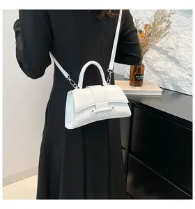 Side view of a white hourglass handbag with curved base and fine leather texture