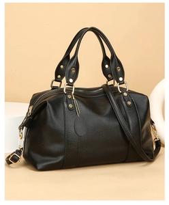 Détail du sac Boston en cuir noir avec ferrures dorées et bandoulière réglable
