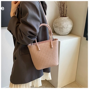 Detail of pink woven tote bag with checkered texture and slim leather shoulder strap