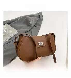 Detailed macro shot of the silver metal turn-lock closure on a brown textured leather bag