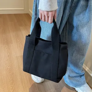 Detailed view of black canvas tote bag with outer pocket for daily commuting