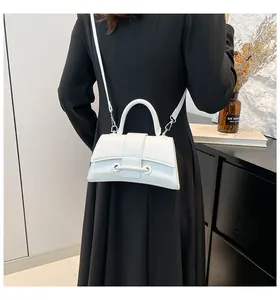 White hourglass handbag with curved base shown as a crossbody bag on a model