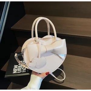 Detail of heart-shaped handbag with bow decoration and adjustable shoulder strap