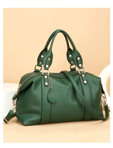 Détail d'un sac à main en cuir grainé vert foncé avec rivets dorés et charm feuille