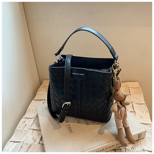 Detail of black woven bucket bag with leather brand tag and cute bunny charm pendant