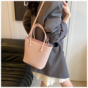 Close-up of pink woven leather texture with adjustable shoulder strap and metal hardware