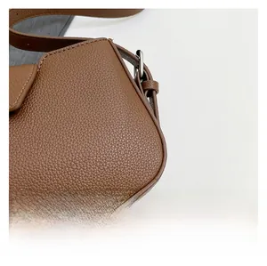 Macro detail of brown lychee texture leather shoulder bag with fine stitching and metal buckle