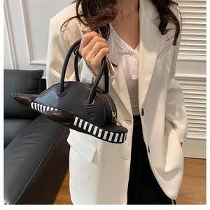 Close-up of creative airplane-shaped black handbag with striped base and gold zipper