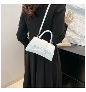 Close-up of white hourglass handbag with curved base and detachable shoulder strap on model