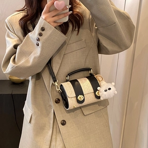 Chic cream straw bucket bag with black leather trim and monster charm shown on model