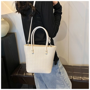 Detail of minimalist beige woven tote bag showing cross-stitch texture and shoulder strap