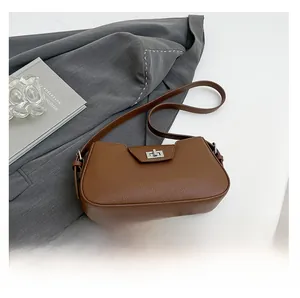 Detailed view of brown leather bag with silver twist lock and grain texture near a phone