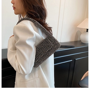 Detail of hand-woven black beaded shoulder bag featuring a retro hollow design on a model