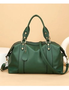 Détail du sac Boston en cuir vert foncé avec fermeture éclair dorée et texture grainée