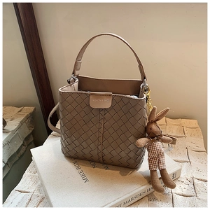 Detail of woven texture bucket bag in light brown with a cute plush bunny charm accessory