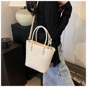 Detail of minimalist woven texture and crossbody strap on this cream tote bag
