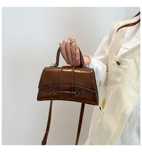Detail of vintage brown oil wax leather bag featuring unique curved base and buckle strap