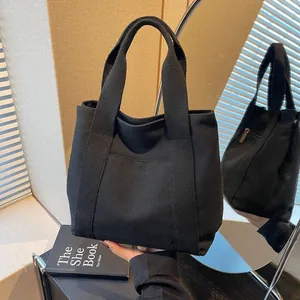 Detail of black canvas tote bag with front pocket and zipper under natural light shadow