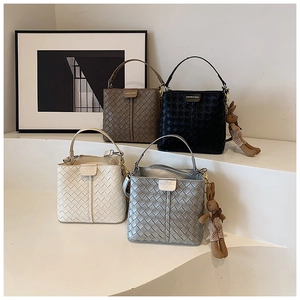 Detailed view of woven bucket bags in brown, black, white, and silver with cute charms