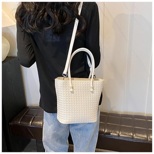 Rear view of a model wearing a white woven bucket bag with elegant shoulder strap
