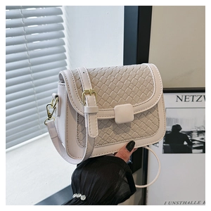 Close-up of the woven texture on this cream-colored shoulder bag with a metal buckle