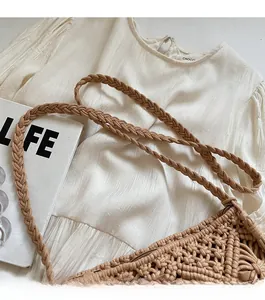Detail of the thick woven shoulder strap and hollow knit texture on a light brown bucket bag