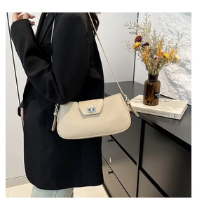 Detail of a beige pebbled leather shoulder bag featuring a silver square twist lock closure