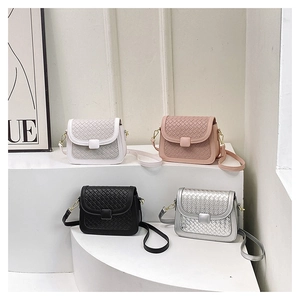 Detail of four colorful woven texture crossbody bags displayed on white pedestals