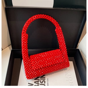Detailed close-up of red handcrafted beaded handbag with luxury display packaging