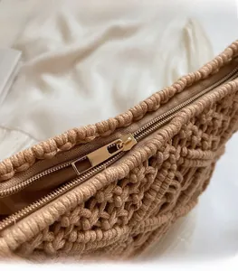 Detail of premium golden metal zipper on beige knitted bucket bag with woven texture