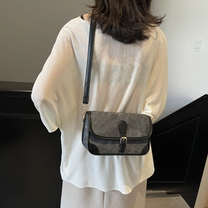 Petit sac bandoulière gris en toile avec bordure en cuir noir porté par un mannequin