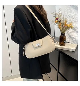Detail of beige textured leather shoulder bag with silver turn-lock on female model