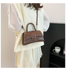 Detail of vintage brown textured hourglass handbag with metal ring buckles and strap