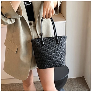 Detail of black woven tote bag with smooth top handles and dense textured pattern