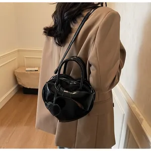 Black heart-shaped bag with large bow detail shown crossbody on a model back view