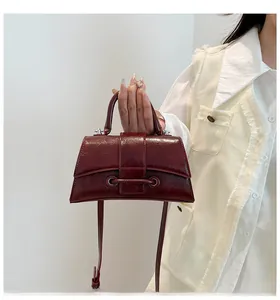 Detail view of burgundy hourglass handbag with cracked leather texture and metal buckle