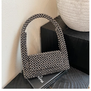 Detailed close-up of handmade silver beaded handbag on a minimalist charcoal wood stand